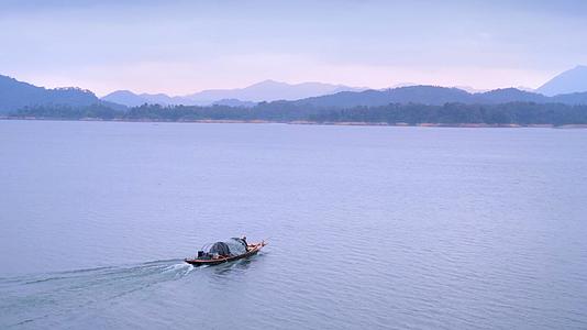 清晨宁静的湖面上驾驶着渔船外出扑鱼的渔民视频的预览图