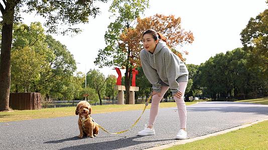 在公园牵着狗跑步休息的少女视频的预览图