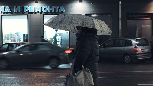 寒冬下雨天城市街边撑伞等待公交车的人视频的预览图