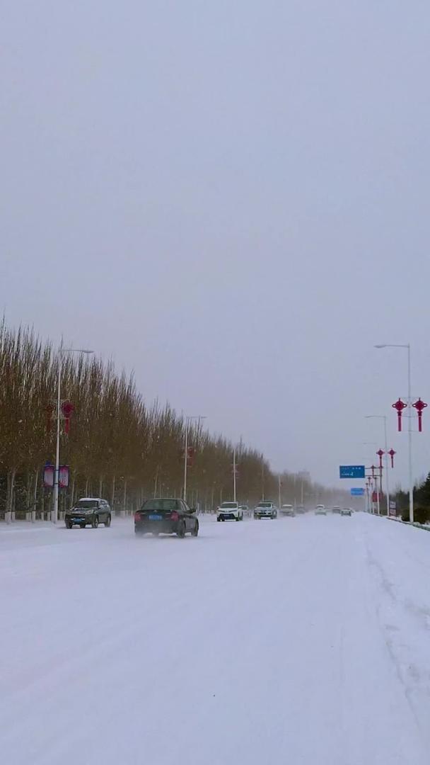 实拍北方飘雪的冬季街道上缓慢行驶的汽车视频的预览图