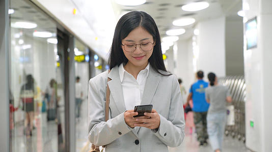 4k白领女性边玩手机边在地铁站内行走视频的预览图
