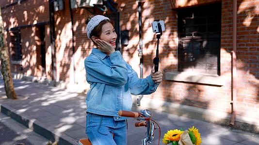 骑行的女青年在路边用手机自拍视频的预览图