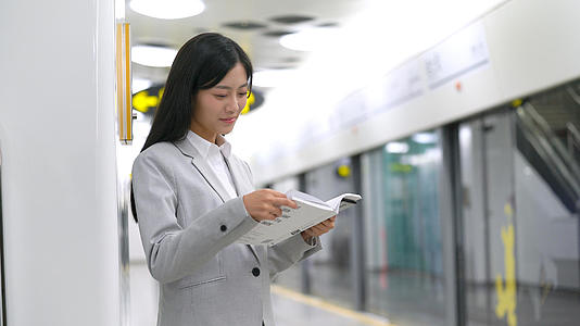 4k穿西装的白领女性在地铁里靠在墙边看书阅读视频的预览图