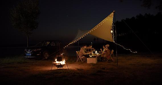 8K夜晚青年在篝火旁的帐篷里进行晚餐视频的预览图