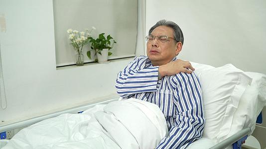 病床上的老人捶着疼痛的肩膀视频的预览图