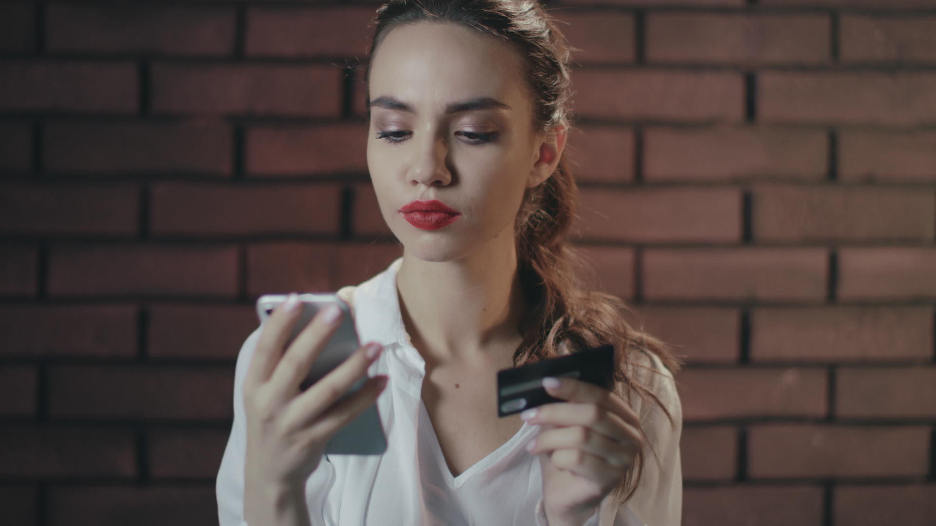 年轻女性使用手机和银行卡在砖房网上购物视频的预览图
