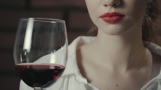 年轻女子手里拿着红酒拿在杯子里视频的预览图