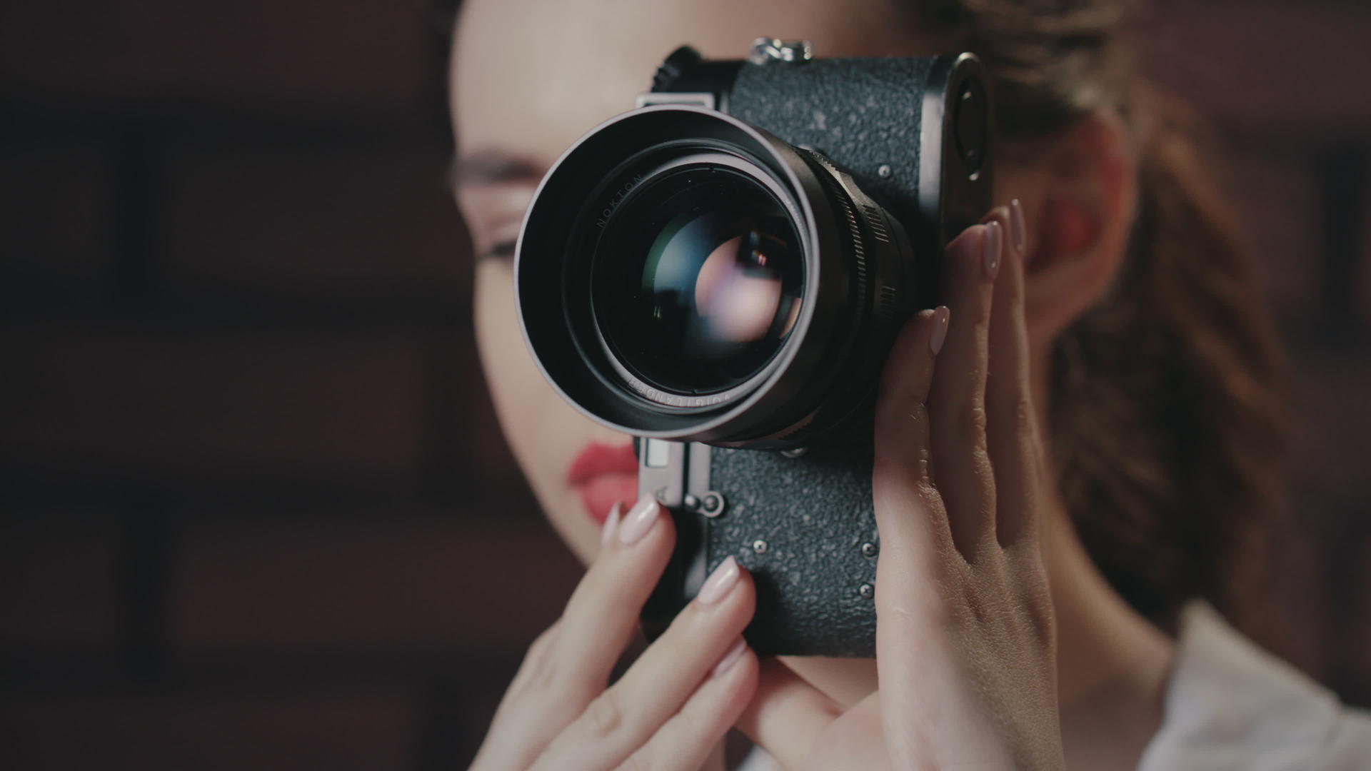 用旧相机在砖墙背景上拍摄的漂亮女人视频的预览图