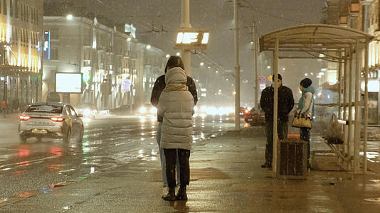 大雪纷飞的夜晚等待公交车的情侣视频的预览图