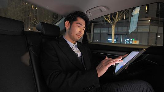 商务人士在汽车后排座位用平板电脑视频的预览图