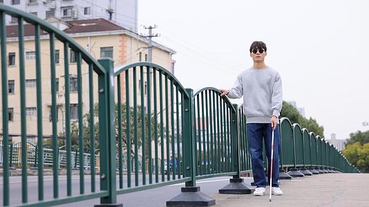 手扶栏杆使用盲杖行走的盲人视频的预览图
