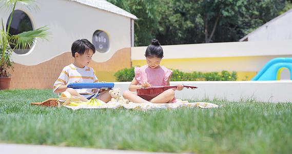 8K夏日可爱小朋友坐在院子里开心弹琴视频的预览图