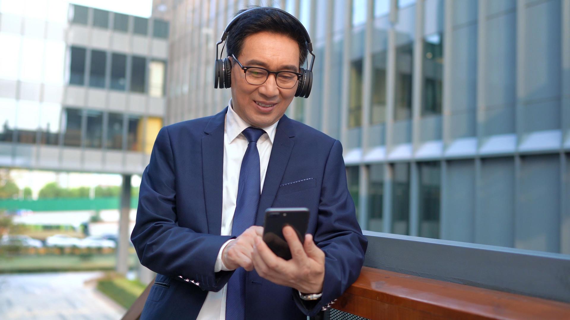 4k商务男性边听音乐边使用手机视频的预览图