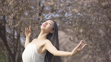 4K实拍春天阳光明媚美女在樱花树下跳舞视频的预览图