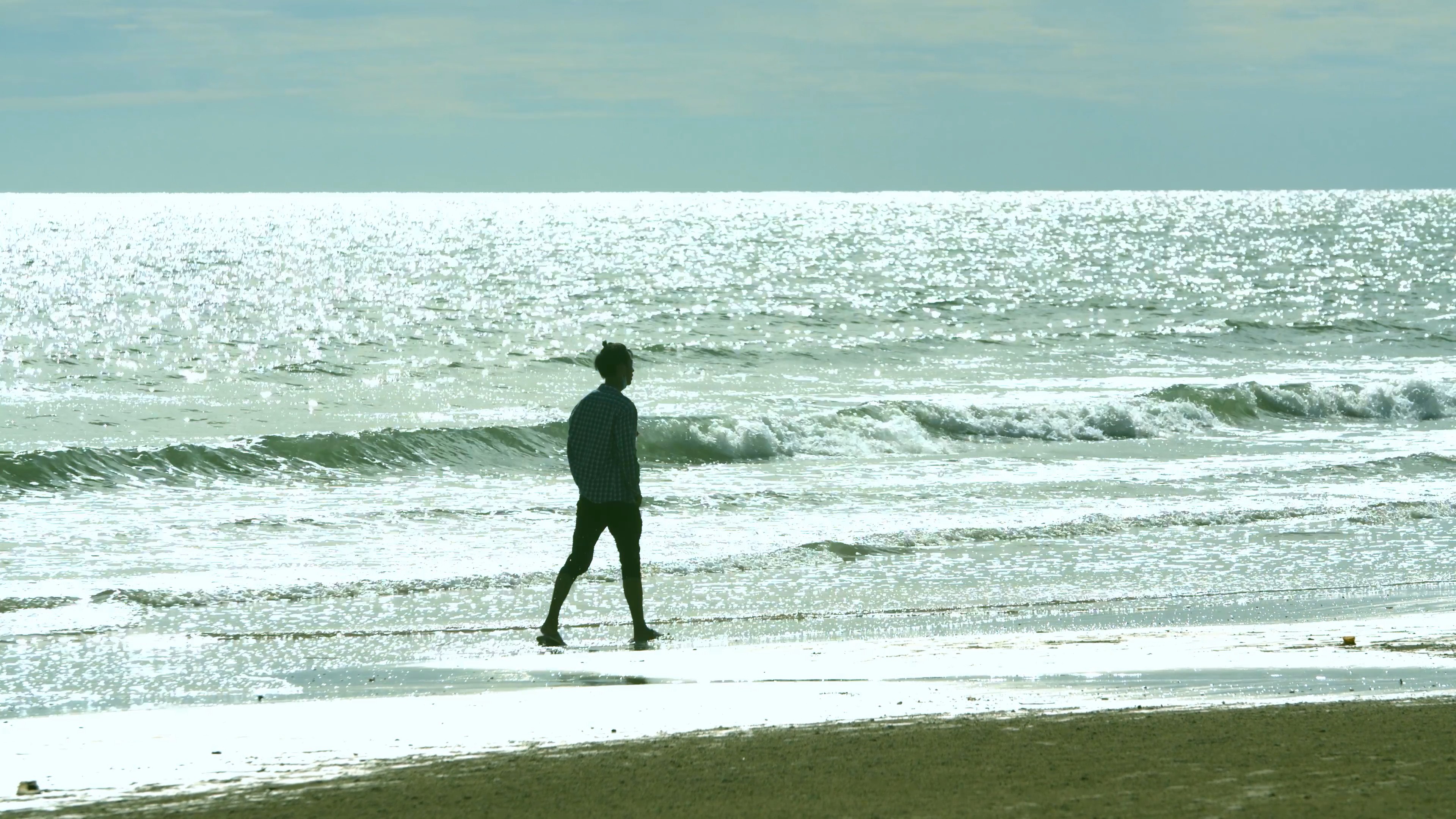 4K逆光实拍走在海边的男子写意视频素材视频的预览图