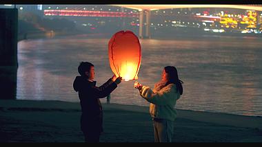 4K实拍夜晚下情侣在河边放孔明灯视频素材视频的预览图