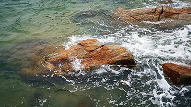 4K实拍海水砂石浪花拍打岩石视频视频的预览图