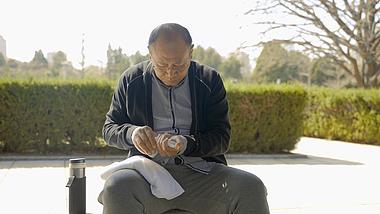 4K老年男性坐公园长椅休息吃药人像视频实拍视频的预览图