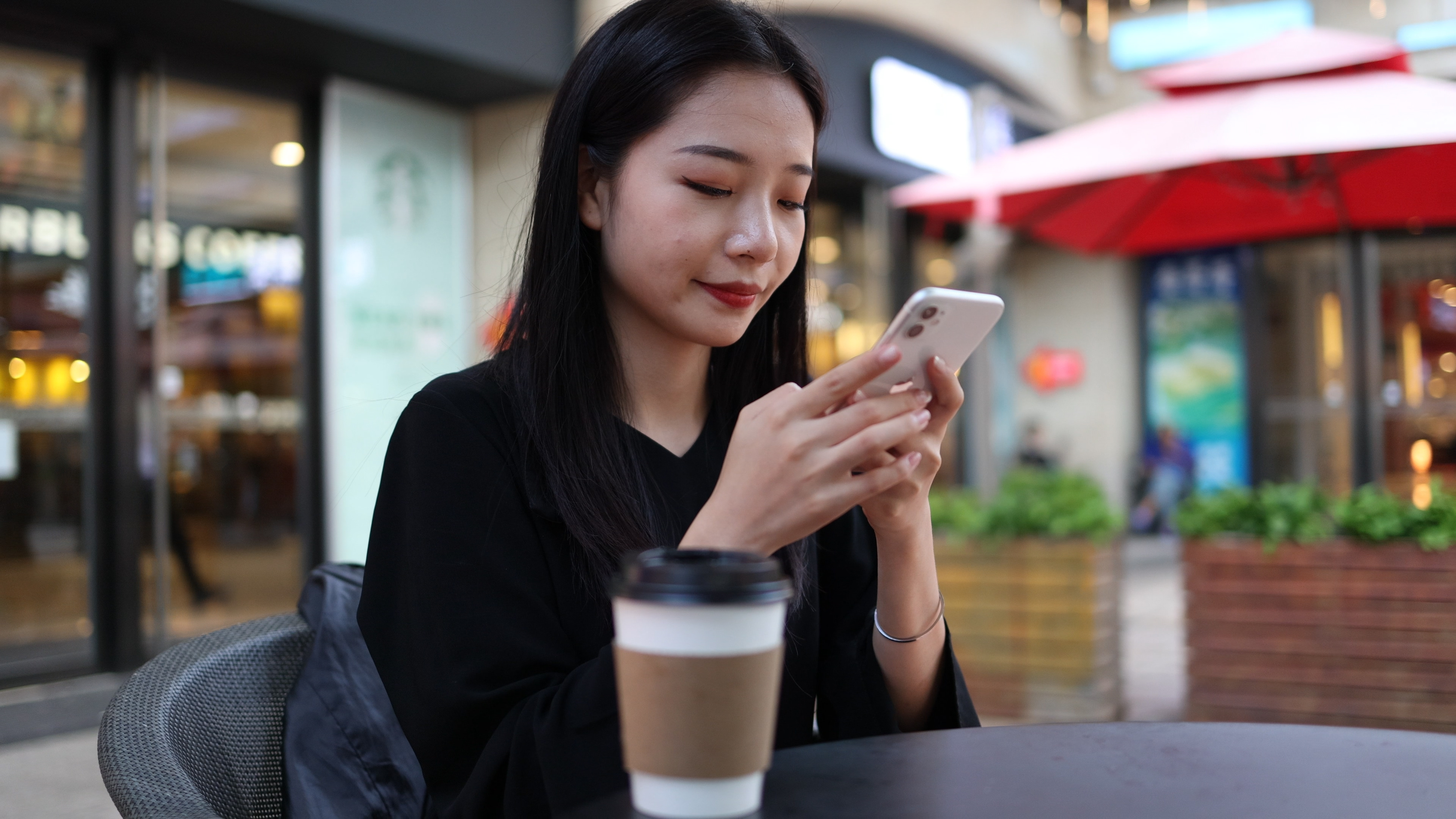 4k商务金融女性在户外咖啡店玩手机视频的预览图