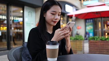 4k商务金融女性在户外咖啡店玩手机视频的预览图