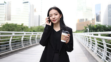 4k商务办公女性在户外拿咖啡打电话视频的预览图