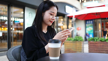 4k商务金融女性在户外咖啡店玩手机交流视频的预览图