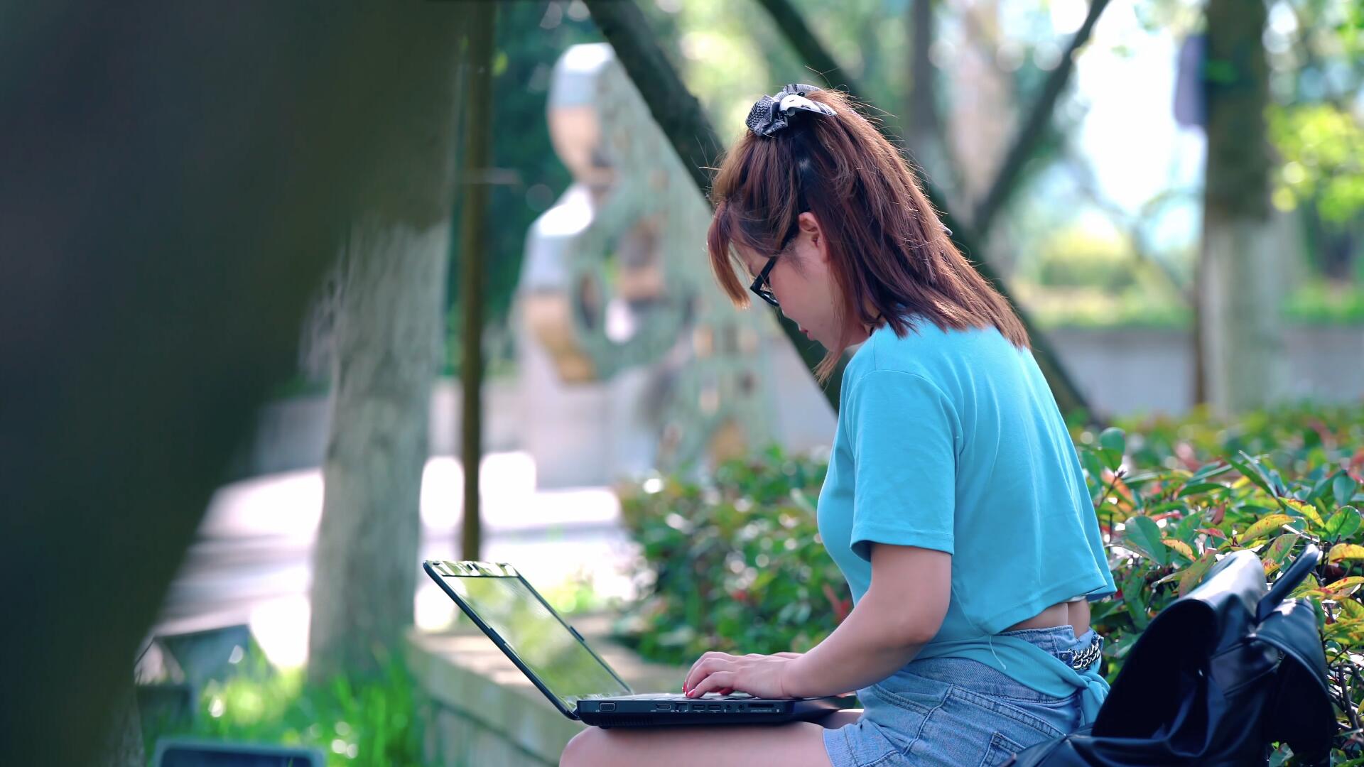 4K女大学生在学校草坪用电脑学习视频的预览图
