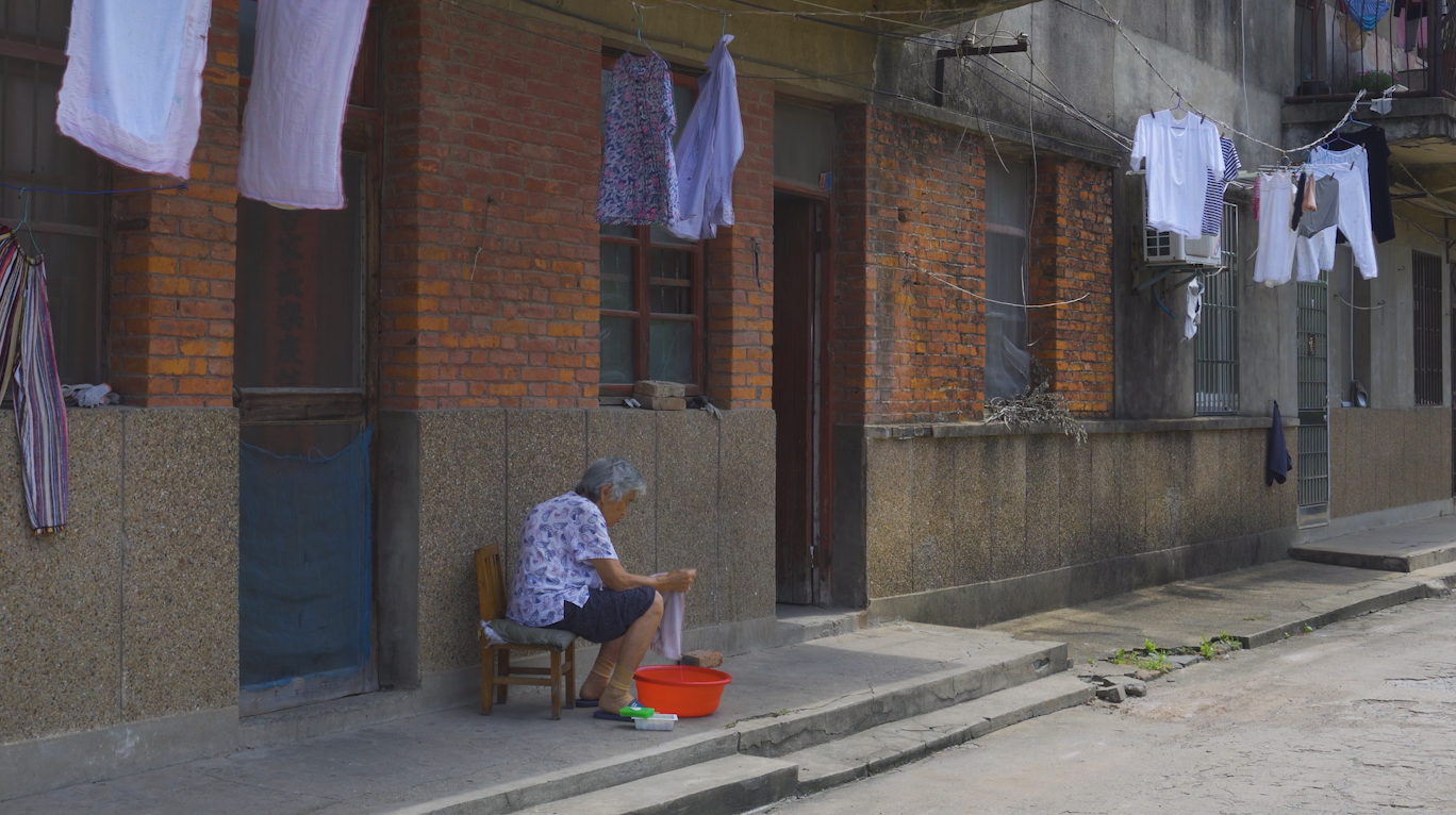 4k实拍乡村小巷空巢老人在门口洗衣服视频的预览图