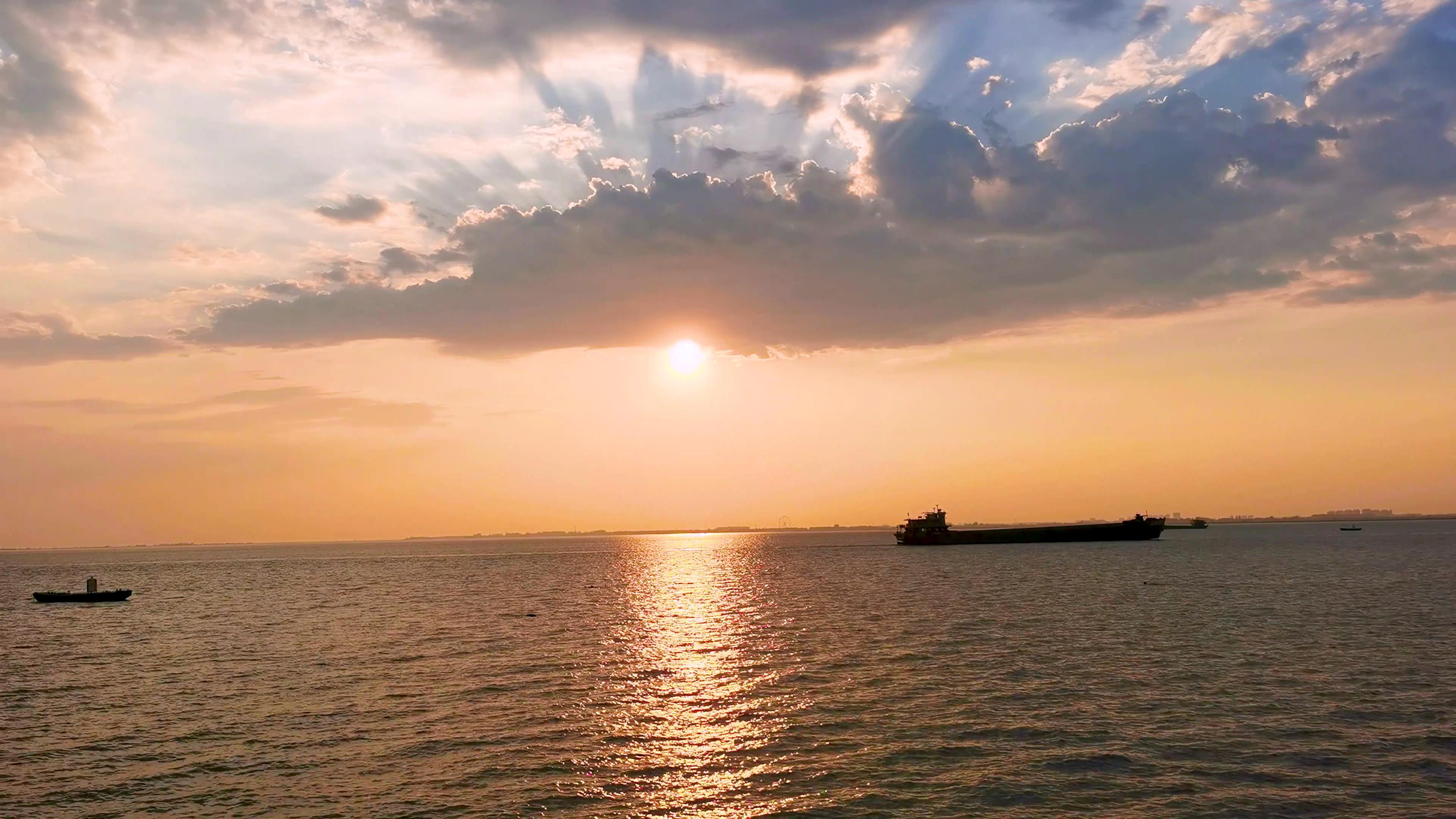 4K实拍夕阳下湖面地平线忙碌的交通货船日落海面视频的预览图