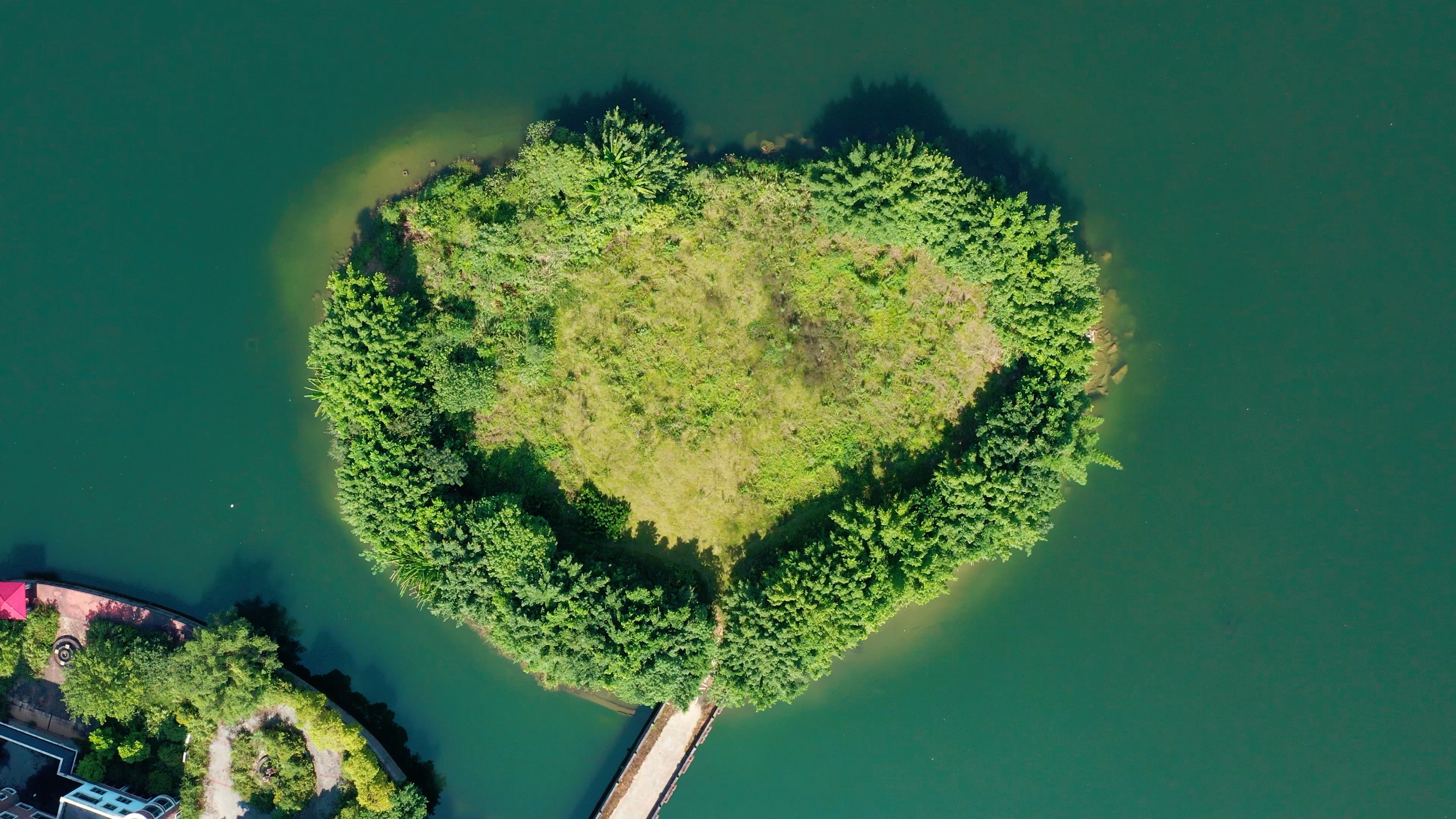 4k航拍环绕上升碧绿湖水中的爱心形小岛视频的预览图