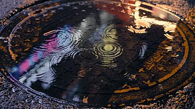 4k雨夜霓虹灯光反射的井盖水面波纹空镜视频的预览图