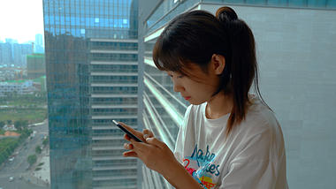 4K实拍女孩坐在窗台玩手机视频的预览图