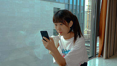 4K实拍清爽女孩喝奶茶玩手机视频的预览图