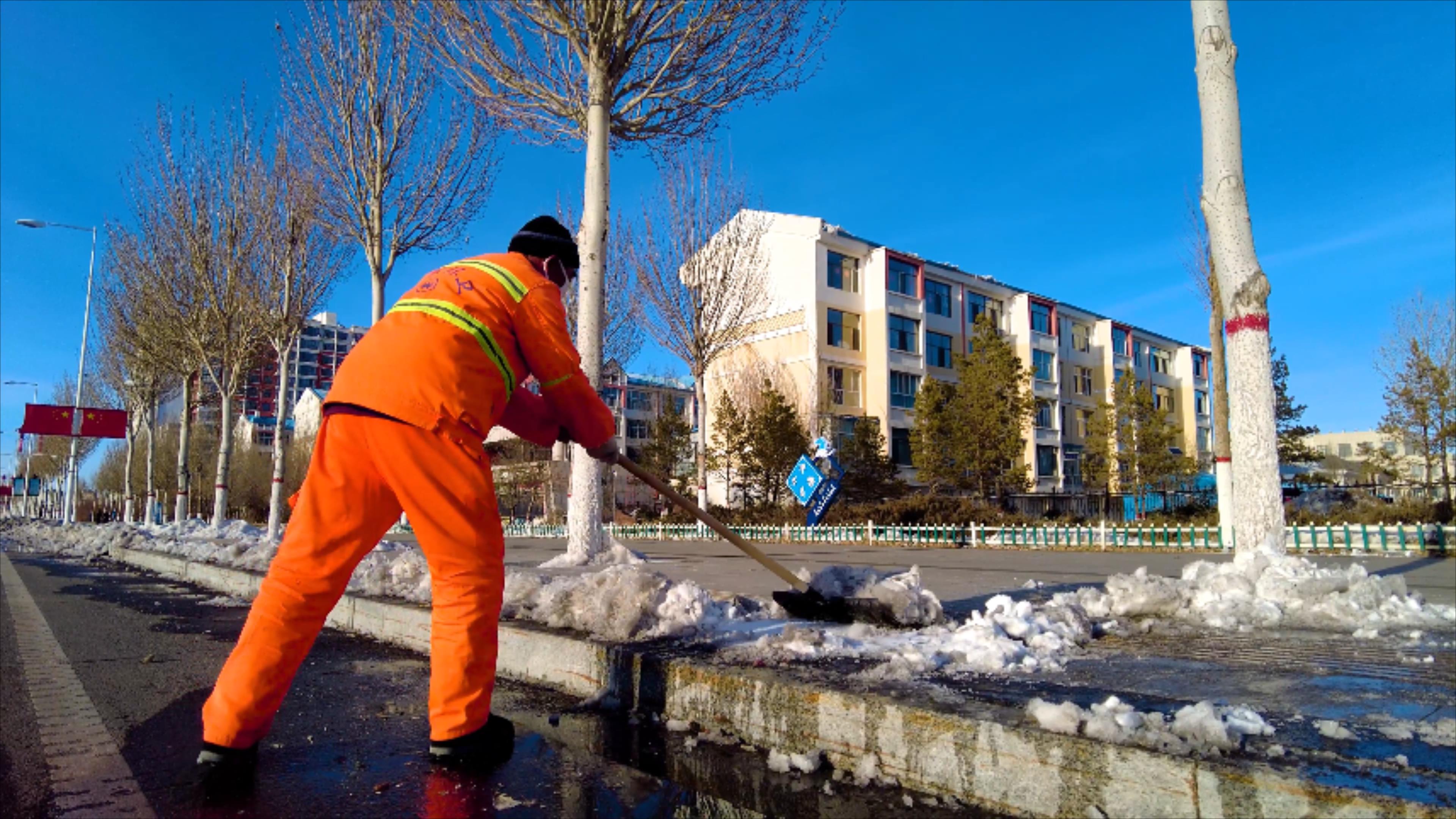 4k拍摄夕阳下环卫工人清扫马路边的积雪视频的预览图