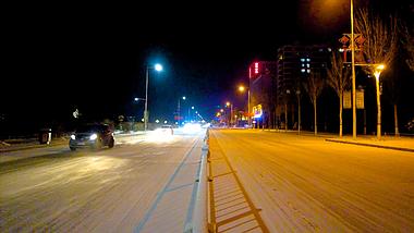 4k拍摄飘雪的夜晚街头缓慢行驶的车辆视频的预览图