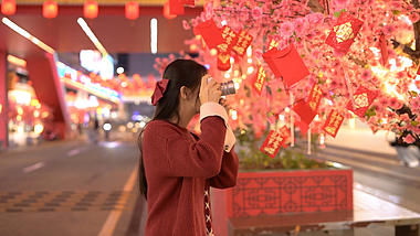 4K唯美新年春节夜晚街道红包树下拍照的少女视频的预览图