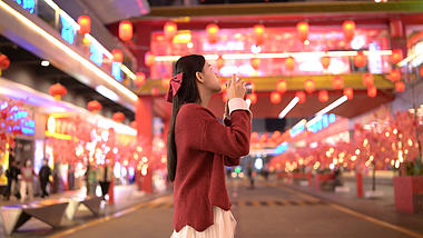 4K唯美新年新春春节夜晚街道灯光下拍照的女孩视频的预览图