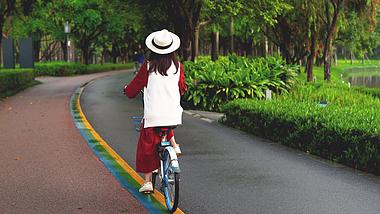 4k实拍春季郊游女性公园骑自行车背影视频的预览图