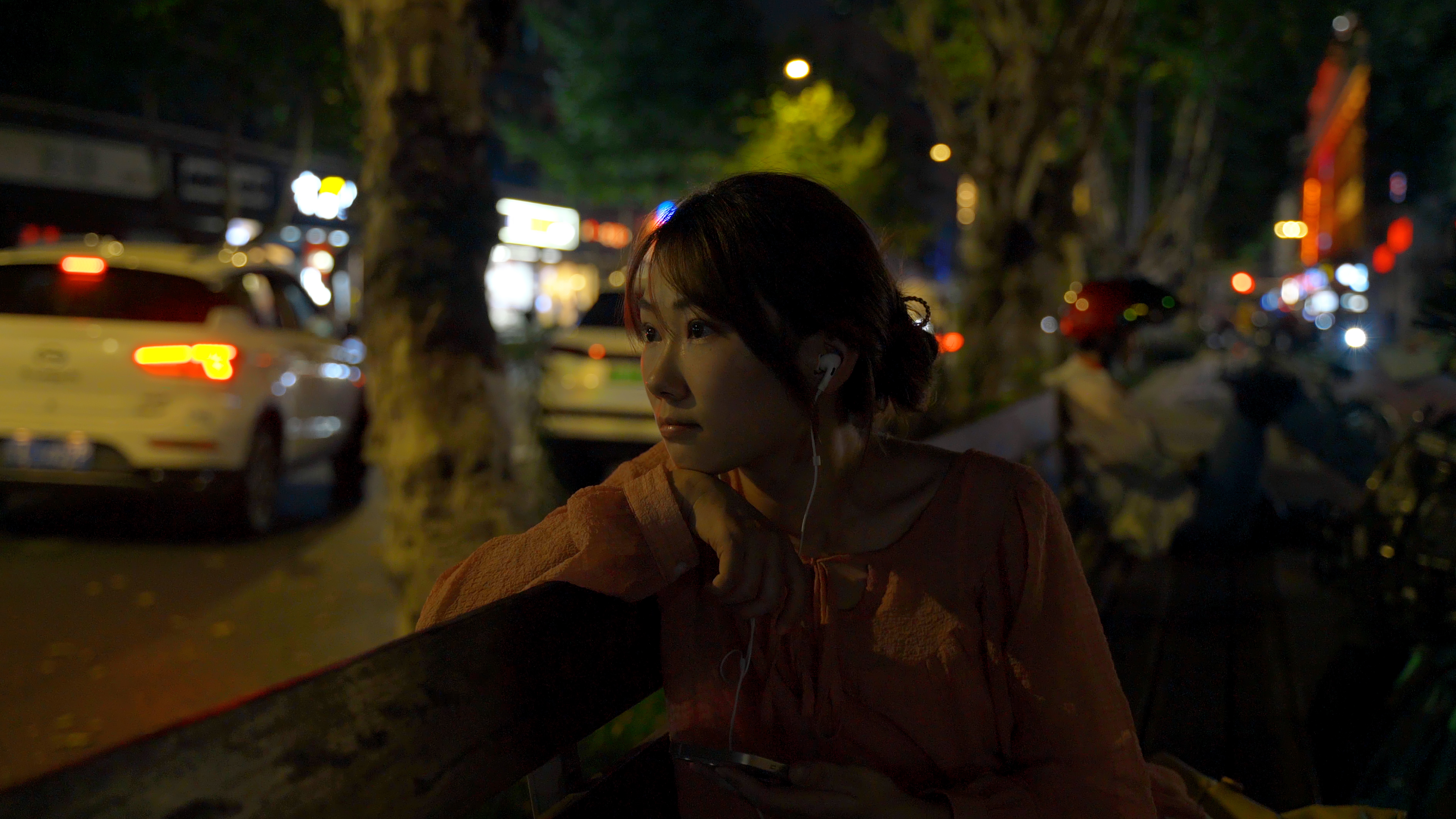 4K实拍夏天夜晚女孩坐在街边马路上悠闲听歌人像视频的预览图