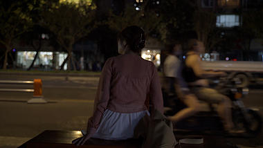 4K实拍夜晚女孩闲坐车水马龙的马路边视频的预览图