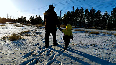 4k老人领着小孩在雪地上漫步背影实拍视频视频的预览图