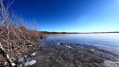 4k逆光实拍蓝天下北方冬天结冰的湖面视频的预览图