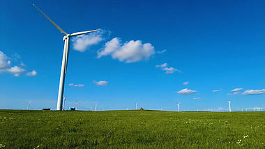 4k唯美实拍蓝天下的大风车和美丽草原视频的预览图